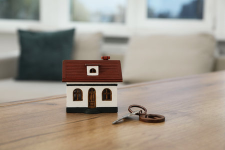 House model and key on wooden table indoorsの写真素材