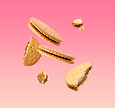 Tasty broken sandwich cookies in air on pink gradient backgroundの写真素材
