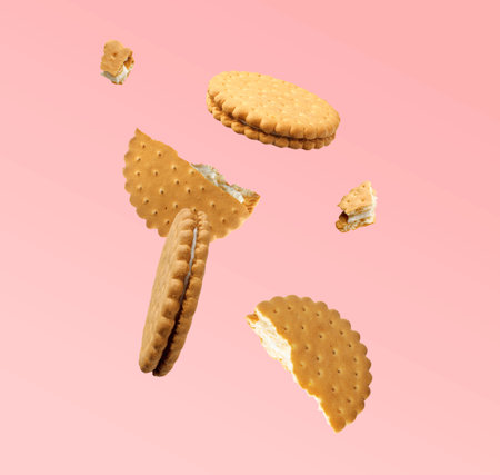 Tasty broken sandwich cookies in air on pink backgroundの写真素材