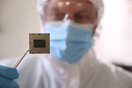 Man in mask holding computer chip on blurred background, selective focusの写真素材