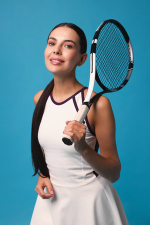 Beautiful young woman with tennis racket on light blue backgroundの写真素材