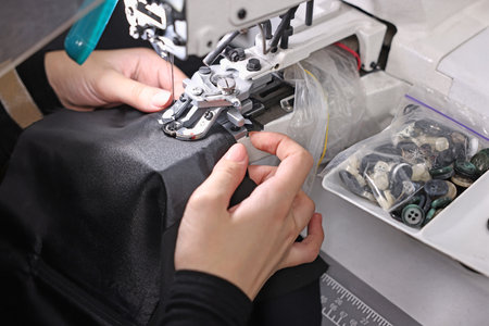 Woman working with sewing machine in professional workshop, closeup