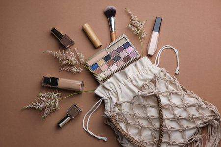Handmade macrame shopping bag with makeup products and spikes on brown background, flat layの写真素材