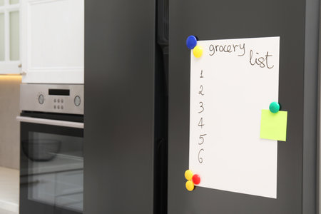 Magnetic board with grocery list and note on refrigerator in kitchenの写真素材