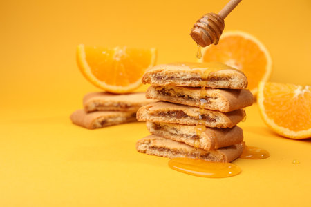 Pouring honey onto cookies on orange background, closeup. Space for textの写真素材