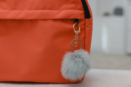 Backpack with faux fur keychain on soft surface indoors, closeup