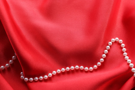Beautiful pearl necklace on red cloth, top view.の写真素材