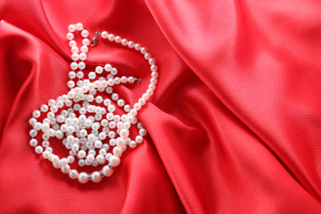 Beautiful bijouterie with pearls on red cloth, top view. Space for textの写真素材