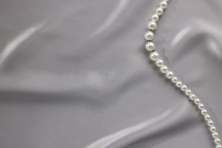 Beautiful pearl necklace on gray silk, top view. Space for textの写真素材