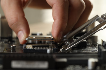 Man installing computer chip onto motherboard at table, closeupの写真素材