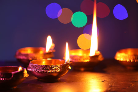 Diwali celebration. Diya lamps on dark table against blurred lights, closeupの写真素材