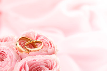 Golden wedding rings and flowers on blurred background, closeup. Space for textの写真素材