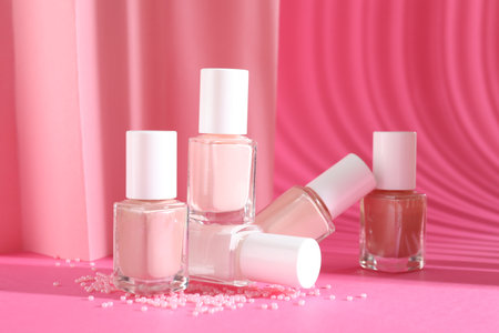 Nail polishes in bottles and beads on pink backgroundの写真素材