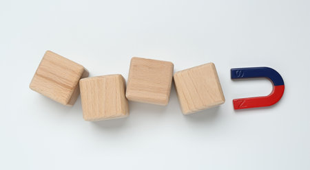 Magnet attracting wooden cubes on white background, flat lay