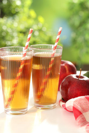 Tasty apple juice in glasses and fresh fruits on white table outdoorsの写真素材