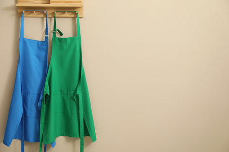 Two chef's aprons hanging on beige wall, space for textの写真素材