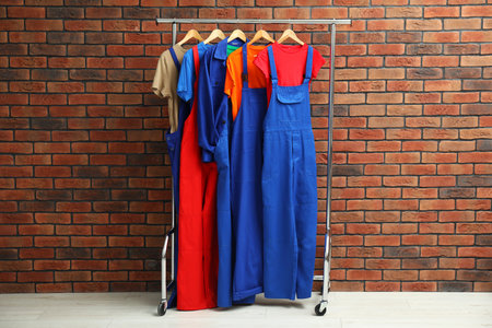 Different workers' uniforms on clothing rack near brick wallの写真素材