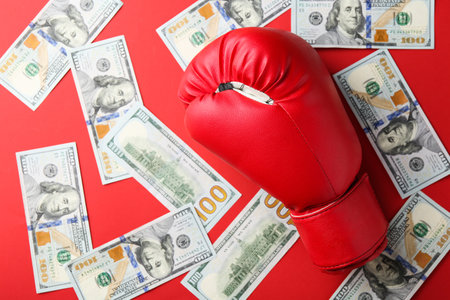 Boxing glove and dollar banknotes on red background, top viewの写真素材