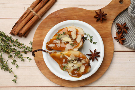 Delicious pears with caramel sauce, almond flakes and spices on white wooden table, flat layの写真素材