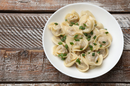 Delicious pelmeni with green onion on wooden table, top view. Space for textの写真素材