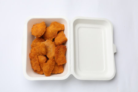 Delicious chicken nuggets in takeaway container on white background, top viewの写真素材