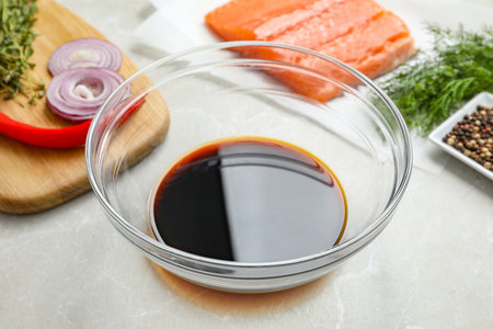 Soy sauce in bowl, salmon fillet and spices on gray marble table, closeupの写真素材