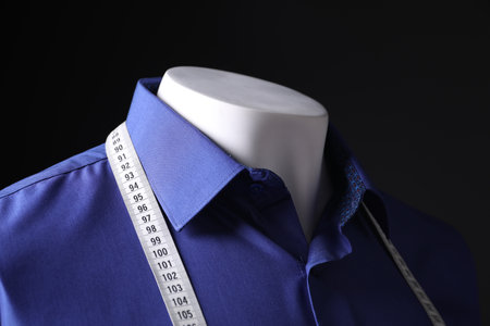 Male mannequin with blue shirt and measuring tape on black background, closeupの写真素材