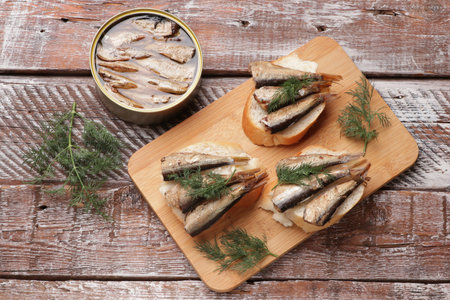 Delicious sandwiches with sprats and dill on wooden table, top viewの写真素材