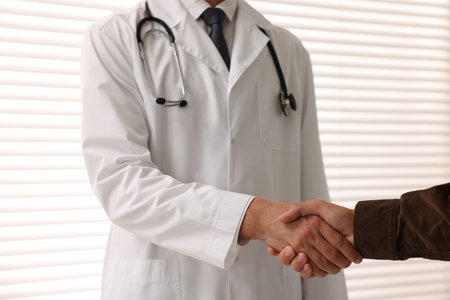 Doctor shaking hands with patient in hospital, closeupの写真素材