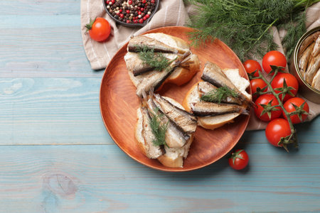 Delicious sandwiches with sprats and dill served on light blue wooden table, top viewの写真素材