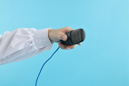 Woman with microphone on light blue background, closeupの写真素材