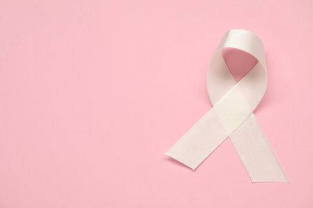 White awareness ribbon on pink background, top view. Space for textの写真素材