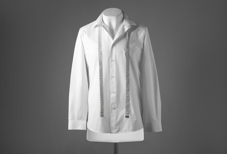 Male mannequin with white shirt and measuring tape on gray backgroundの写真素材