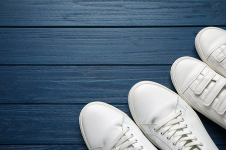 Big and small shoes on blue wooden table, top view. Space for textの写真素材