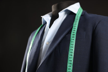 Male mannequin with jacket, shirt and measuring tape on black background, closeupの写真素材