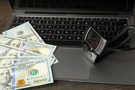 Laptop with web camera and money on wooden surface, closeupの写真素材
