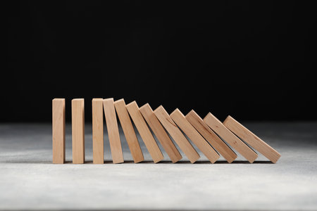Domino effect. Wooden blocks falling on gray tableの写真素材