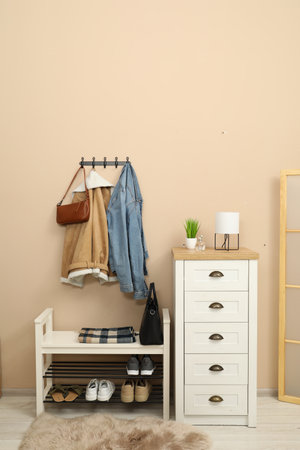 Coat rack with clothes, mirror, shoe storage bench and chest of drawers in hallway. Interior designの写真素材