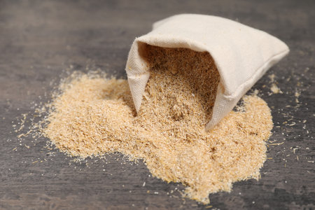 Oat bran in burlap bag on gray table, closeupの写真素材