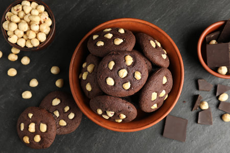 Tasty chocolate cookies with hazelnuts on black table, flat layの写真素材
