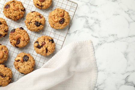 Delicious oatmeal cookies with raisins and nuts on white marble table, top view. Space for text