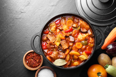 Delicious stew with vegetables in pot and ingredients on gray textured table, flat lay. Space for textの写真素材