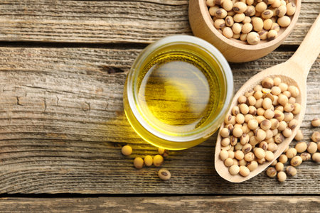 Cooking oil and soybeans on wooden table, flat lay. Space for textの写真素材