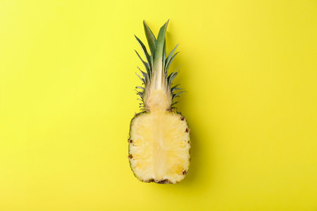 Half of fresh pineapple on yellow background, top view