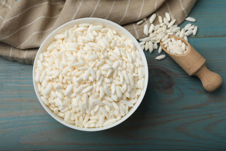 Puffed rice in bowl and scoop on light blue wooden table, flat layの写真素材