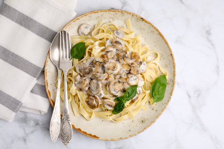 Delicious pasta with mushrooms and basil served on white marble table, top viewの写真素材