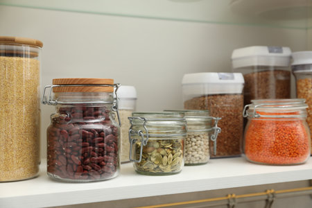 Different types of cereals, seeds and legumes in containers in closetの写真素材