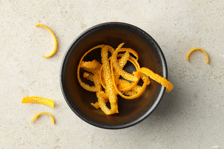 Fresh orange zest in bowl on light textured table, flat layの写真素材