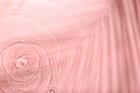 Rippled surface of clear water on pink background, top viewの写真素材