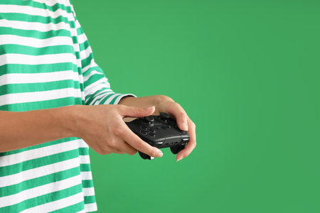 Woman playing video games with controller on green background, closeup. Space for text